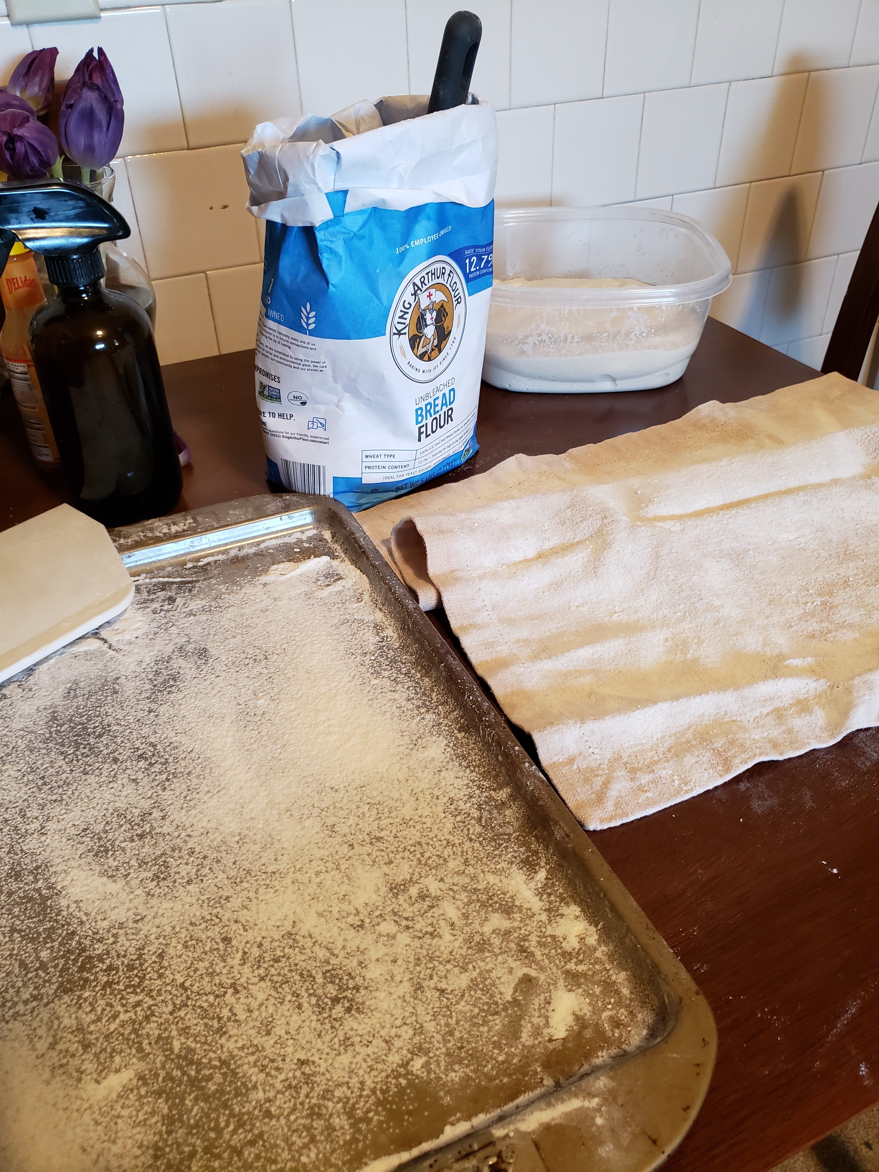 Floured surface on top of a baking sheet (testing the idea but it makes the space too small). Ciabatta dough and floured kitchen towel.